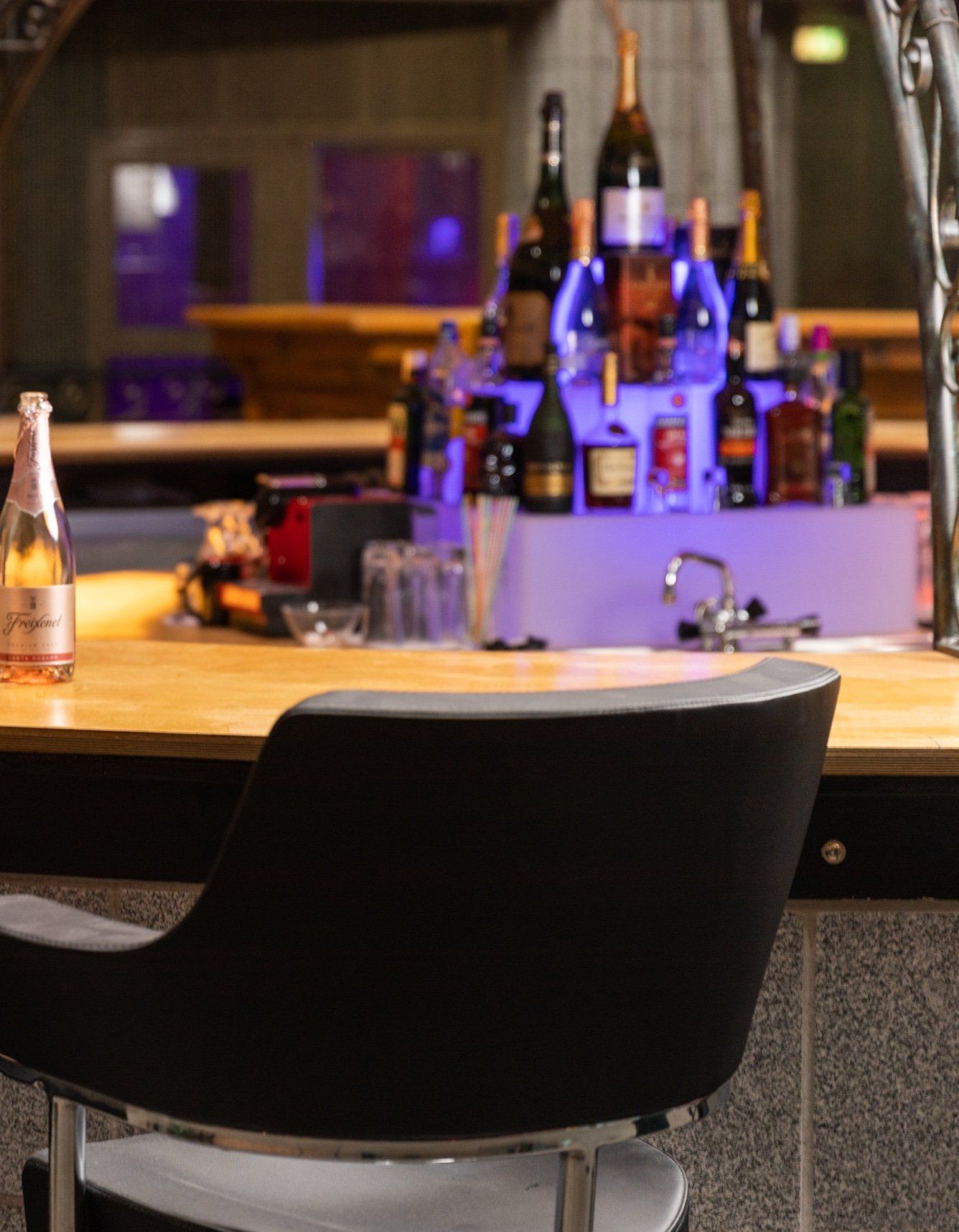 Bar mit Sektflasche und beleuchtetem Flaschenregal